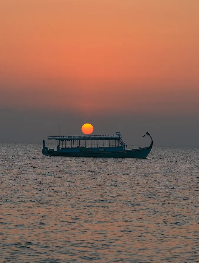 silhouette of boat on sea during sunset
